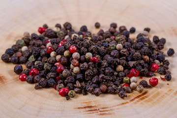 Black, white and red pepper peas on a wooden background