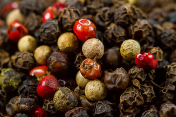 Black, white and red pepper peas on a wooden background