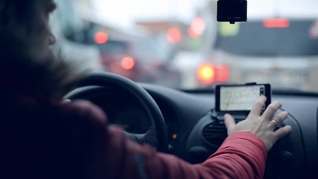 A man gets into the car and turns on the navigator on the smartphone