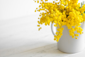 Bouquet of mimosa flowers on white wooden background. Springtime.