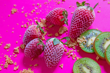 Beautiful picturesque breakfast with frozen strawberries and cut kiwi fruits. Healthy delicious dessert