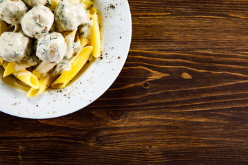 Meatballs with pasta and sauce on wooden table