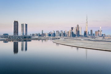 Fototapeta na wymiar Beautiful colorful sunrise lighting up the skyline and the reflection of Dubai Downtown and D3 Dubai Design District. Dubai, United Arab Emirates.