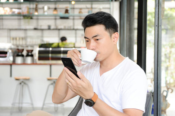 Fototapeta na wymiar Asian man using smartphone for shopping online while drinking some coffee,A man using internet banking in smartphone,Shopping online in coffee shop,Business and investment online