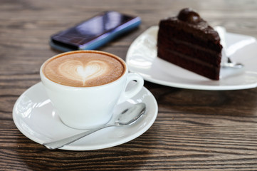 Cappuccino coffee in white cup lay on wooden table,Relax time with coffee and chocolate cake,Art of coffee,Chocolate cake put on table,selective focus