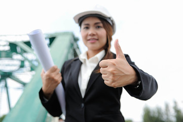Female engineer holding a blueprint and thumb up,Engineer women smiling portrait picture,Engineer women show hand sinage that's mean Like