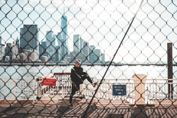 Male athlete warming up and training in big city near port. Sportsman stretching legs near urban quai and preparing for running
