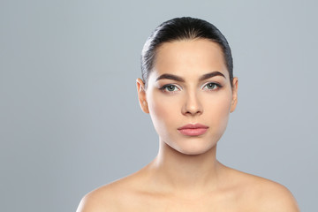 Young woman wearing beautiful lipstick on color background