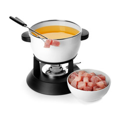 Fondue pot with oil and raw meat on white background