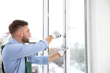 Fototapeta premium Construction worker adjusting installed window with screwdriver indoors