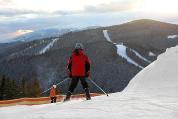Man skiing on snowy hill in mountains. Winter vacation