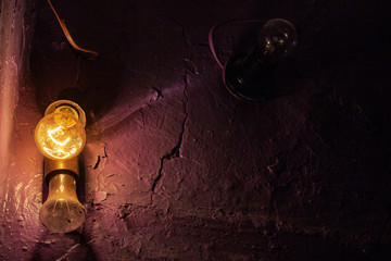 glowing and burnt out old dirty light bulbs on the background of painted concrete wall