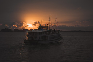 Boat sailing in Ha Long bay Vietnam at sunset