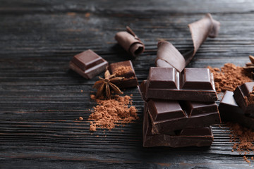 Pieces of black chocolate on wooden table. Space for text