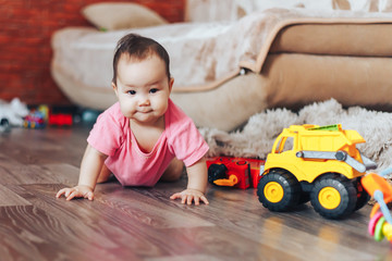 little baby starting to crawl at home in pink clothes