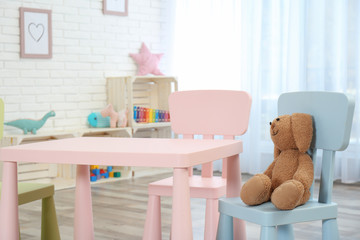 Cozy kids room interior with table, chairs and toy rabbit