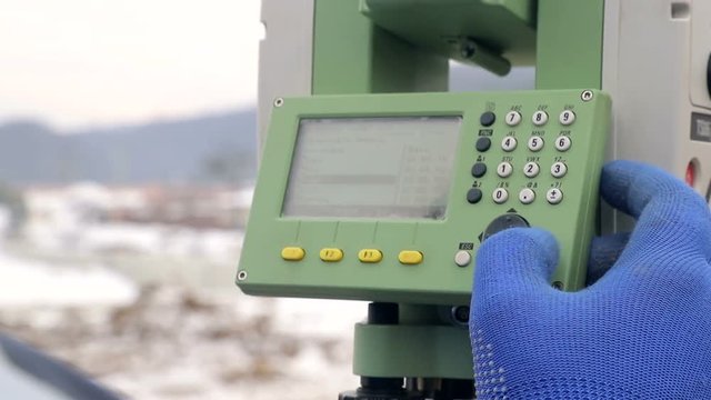 Close-up finger that pushes the Surveyor buttons at work measuring the distance. The concept of winter construction