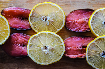 Red fish and lemon slices on wooden background