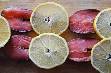 Red fish and lemon slices on wooden background