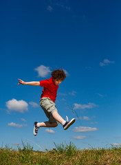 Boy jumping, running against blue sky