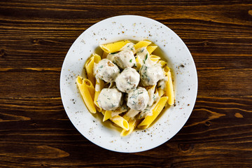 Pasta with meatballs and sauce on wooden table