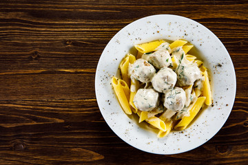 Pasta with meatballs and sauce on wooden table