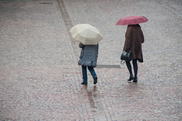 portrait of women with grey umbrella on cobbles place in the city on back view