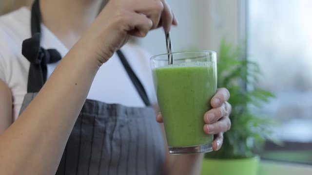 Young woman holding vegetable smoothie in glass