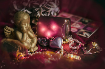 Composition with a golden cupid, gift box, heart, hydrangea flower in mystical dark lighting.