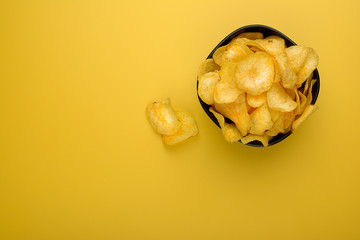 Homemade Cheese and Onion Potato Chips on yellow background (selective focus; close-up shot)