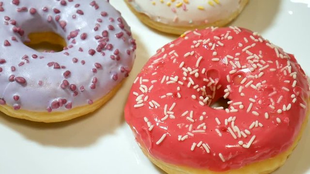 Three donuts with colorful sprinkles on white plate. Unhealthy sugar abuse addiction concept