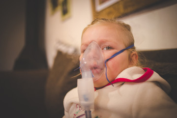 Close up image of a toddler girl with a nebulizer, inhaling medicine to clear up chest infection.