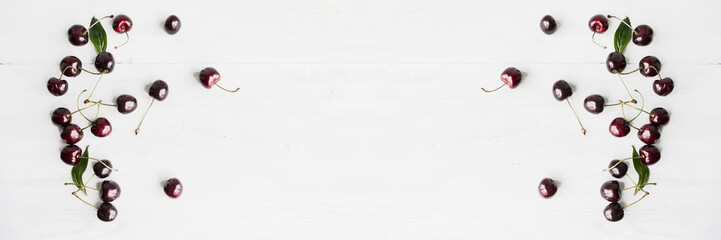 Bleached and whitened by design. Summer food background - ripe cherry berries on white wooden table. Wide panoramic image. Copy space.