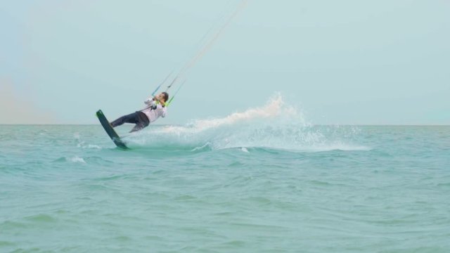 businessman rides a kite in the tropical ocean and performs tricks Slow motion