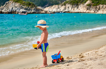 Fototapeta na wymiar Toddler boy on beach with toys