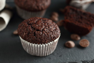 Chocolate homemade cupcakes muffins on a black background with chocolate drops in the background. Bakery style. Dark food photo