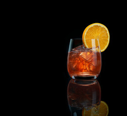 Alcoholic cocktail with orange slice on black background with copy space
