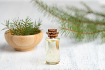 Obraz na płótnie Canvas Pine essential oil in a glass bottle. Soft focus. White wooden background.