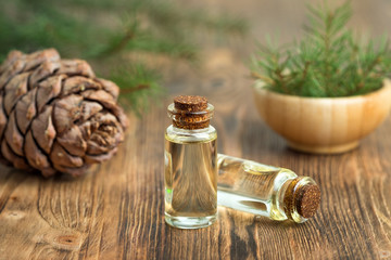 Cedar essential oil in a glass bottle. Soft focus. Wooden background.