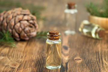 Cedar essential oil in a glass bottle. Soft focus. Wooden background.