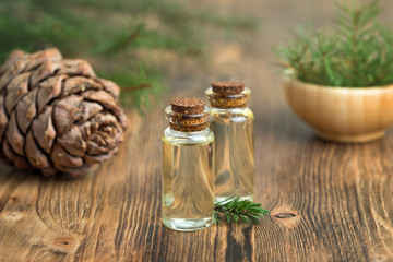 Cedar essential oil in a glass bottle. Soft focus. Wooden background.