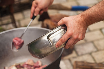 Fototapeta na wymiar Cook adds pieces of lamb in a cauldron