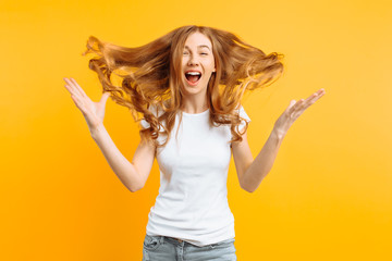Young shocked girl shocked by good news, screaming with happiness over yellow background - obrazy, fototapety, plakaty