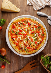 Tasty pizza on the wooden background with ingredients around. Flat lay with top view