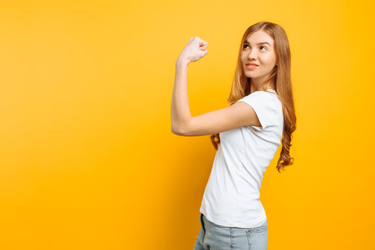 Of A Pensive Girl In A White T-shirt Showing The Muscles Of The Hands On A Yellow Background