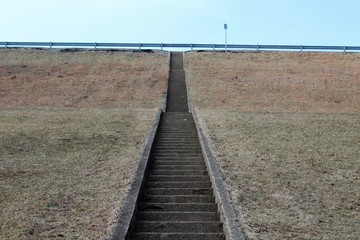 Naklejka premium The cement steps up the green grass hill landscape.