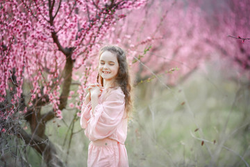 Fototapeta na wymiar Beautiful young woman in pinkstylish garden dress blooming sakura