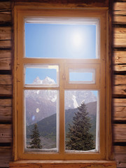view of the nature and landscape of the snow capped peaks of the Mountains from the window of a wooden log house   summer day