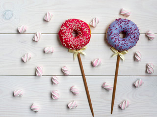 Two red and light purple donuts like candies with marshmallow
