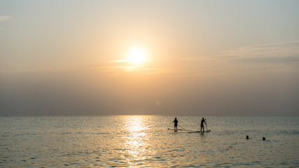 Fototapeta premium Stand up paddle board at sunset on the Phu Quoc beach Vietnam,travel concept,beach activity,Person stand up paddle boarding at dusk beautiful sunset colors